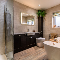 Free standing bath with modern fitted furniture, frameless shower cubicle, fully tiled with click lock flooring