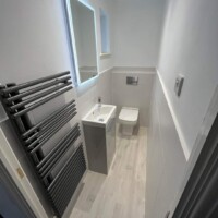 Cloakroom with free-standing basin unit, back-to-wall toilet with hidden cistern, modern towel rail and LED mirror
