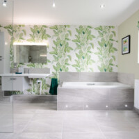 Disabled wet room featuring tiled in bath area with LED light, bespoke basin and leaf print wallpaper