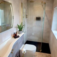 Curved fitted furniture featuring SMO curved sparkling basin, black slate shower tray, and gold fittings