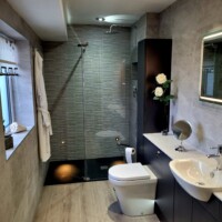 Modern runner fitted furniture with black slate shower tray, ambient shower lighting, and textured wall tile