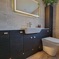 Modern fitted furniture run including under unit lighting with comfort height toilet and LED mirror